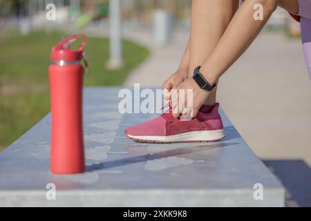 Gros plan des pieds d'une fille attachant les lacets de sa sneaker. Banque D'Images