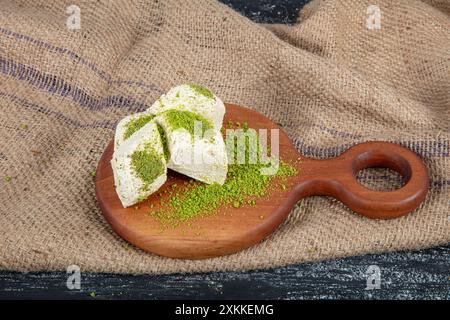 Pistache halva (Halvah). Halva avec des pistaches sur une table en bois rustique. Gros plan d'une assiette en bois avec halva de pistache turque traditionnelle et tranches Banque D'Images