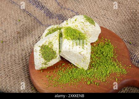 Pistache halva (Halvah). Halva avec des pistaches sur une table en bois rustique. Gros plan d'une assiette en bois avec halva de pistache turque traditionnelle et tranches Banque D'Images