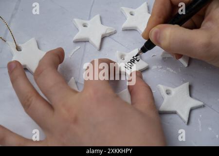 Mot d'écriture de classe de maître HOPE Creator utilise de l'argile sèche blanche à l'air pour faire le décor aux vacances d'arbre de Noël. Créer une activité de loisirs qui implique les doigts. Bricolage artisanat d'art moderne Banque D'Images