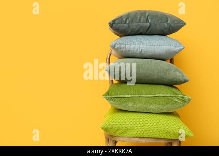 Pile de coussins sur la chaise près du mur jaune dans la chambre Banque D'Images