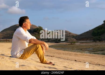 17.11.2023, Indonésie, Lombok, Kuta - homme assis sur la plage et bronzer. 00S231117D433CAROEX.JPG [AUTORISATION DU MODÈLE : OUI, AUTORISATION DU PROPRIÉTAIRE : NON C) C Banque D'Images