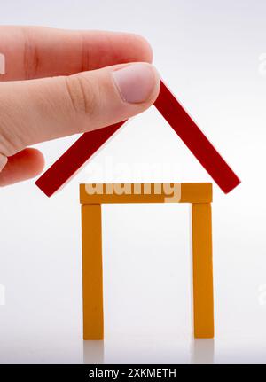 Hand holding pièces domino formant une forme de maison Banque D'Images