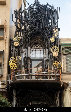 Façade de bâtiment artistique décorée de tubes noirs et d'engrenages dorés Banque D'Images