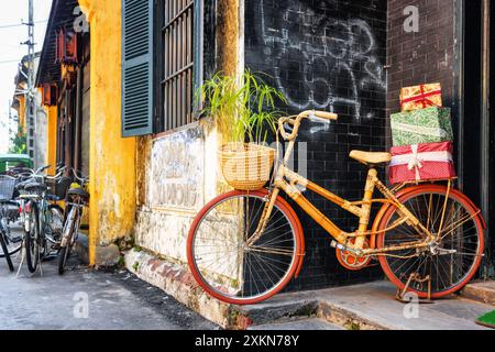 Vélo en bambou fait à la main avec des boîtes-cadeaux sur le rack garé près du mur Banque D'Images