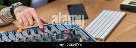 Un homme asiatique ajuste les niveaux sonores sur une table de mixage. Banque D'Images