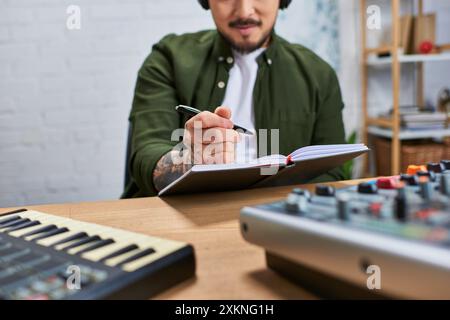 Un homme asiatique portant une tenue décontractée travaille sur une nouvelle pièce musicale dans un studio d'enregistrement. Banque D'Images