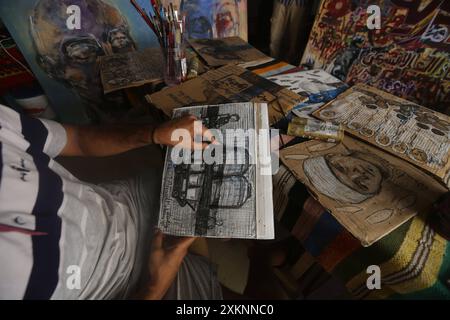 Un plasticien palestinien Ahmed Muhanna peint des tableaux dans son atelier du camp de Deir al-Balah Un plasticien palestinien Ahmed Muhanna peint des tableaux dans son atelier du camp de Deir al-Balah, dans le centre de la bande de Gaza , le 24 juillet 2024. Al-Banna utilise le papier des boîtes en carton destinées à distribuer l'aide humanitaire aux déplacés, pour peindre des peintures qui expriment la vie dure des Palestiniens à la lumière de la guerre israélienne continue dans la bande de Gaza. Photo Naaman Omar apaimages Dair El-Balah Gaza Gaza territoire palestinien 240724 Dair El Balah NAA 0020 Copyright : xa Banque D'Images