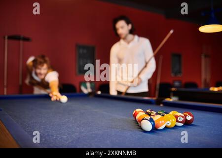 Des amis jouent au billard dans un pub faiblement éclairé. Banque D'Images