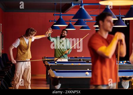 Les amis profitent d'une partie de billard dans une salle de billard bien éclairée. Banque D'Images