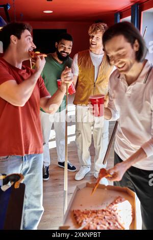 Des amis se sont rassemblés autour d'une table de billard, dégustant pizza et boissons. Banque D'Images