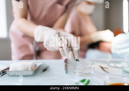 Mains rapprochées d'une infirmière tenant une seringue avec des vaccins liquides travaillant dans un hôpital moderne. Gros plan de médecin féminin méconnaissable dans le remplissage de gants en latex Banque D'Images