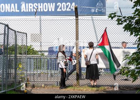 24 juillet 2024, manifestation pacifique et veillée devant le salon aéronautique international de Farnborough dans le Hampshire, Angleterre, Royaume-Uni, contre le commerce des armes. Les manifestants appellent à cesser de vendre des armes qui causent la mort et la destruction en Palestine et dans le monde entier. La manifestation était organisée par plusieurs groupes activistes, Greater Rushmoor action for Peace, East Berkshire Palestine Solidarity Campaign, Quakers et CAAT (campagne contre le commerce des armes). Sur la photo : femme tenant le drapeau palestinien à l'extérieur du terrain du spectacle aérien. Banque D'Images