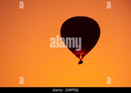 Silhouette de montgolfière volant dans le ciel orange au lever du soleil Banque D'Images