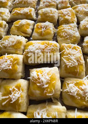 Pâtisseries maison fraîchement préparées, recouvertes de fromage râpé et d'oeufs lavés prêts pour la cuisson Banque D'Images