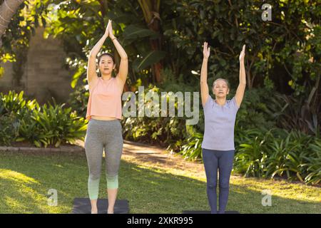 Pratiquer le yoga en plein air, grand-mère asiatique et petite-fille s'étirant sur des tapis de yoga dans le jardin Banque D'Images