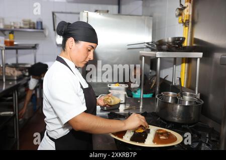 Oaxaca, Mexique. 23 juillet 2024. Un chef prépare des plats traditionnels avec de la sauce taupe dans un restaurant de la ville d'Oaxaca, capitale de l'État d'Oaxaca, au Mexique, le 23 juillet 2024. Oaxaca cuisine est une cuisine régionale du Mexique, centrée sur la ville d'Oaxaca. La nourriture traditionnelle telle que la sauce taupe, la sauterelle et la boisson Mezcal sont populaires parmi la population locale et les touristes. Crédit : Li Mengxin/Xinhua/Alamy Live News Banque D'Images