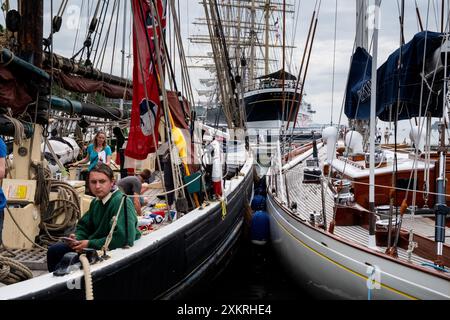 MARIEHAMN, Åland, FINLANDE - 24 JUILLET 2024 : les équipages étudiants des grands voiliers se détendent sur le pont après leur voyage de Turku dans le Finalnd continental à Mariehamn. Premier jour des trois jours Åland Stage de la course de grands voiliers 2024 dans le port principal, Mariehamn, Åland, Finlande. Photo : Rob Watkins/Alamy Live News. INFO : la Tall Ships Race est un événement annuel de voile mettant en vedette des grands voiliers historiques et modernes. Il promeut l'amitié internationale et la formation des jeunes, attirant des participants et des spectateurs du monde entier pour célébrer le patrimoine maritime et l'art de la voile traditionnelle. Banque D'Images