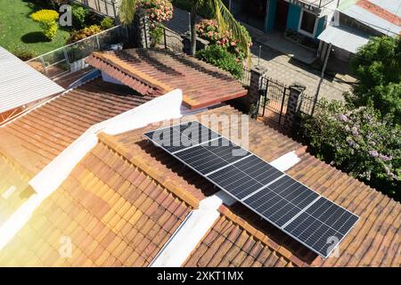 Toit de maison recouvert de panneaux solaires en fond tropical Banque D'Images