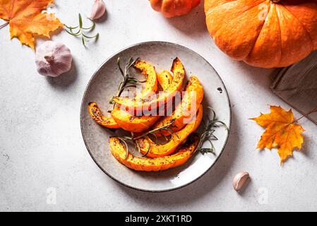 Tranches de citrouille rôties à l'ail et aux herbes. Citrouille cuite au four, plat d'accompagnement d'automne de saison ou repas végétalien grillé sur l'assiette, vue de dessus. Banque D'Images