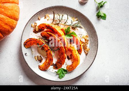 Citrouille rôtie avec yaourt grec, ail et herbes, vue de dessus. Recette chaude de salade de citrouille épicée d'hiver avec fromage de chèvre labneh mou et oignon frit. Banque D'Images