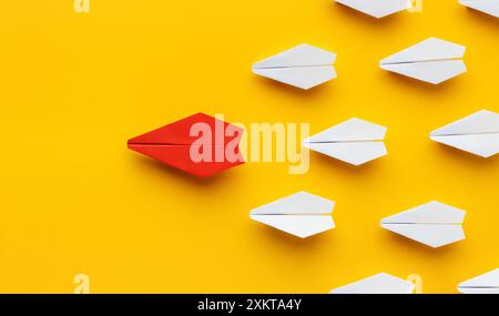 Leadership d'opinion. Avion de papier rouge menant d'autres colorés, influençant la foule, fond jaune, panorama Banque D'Images