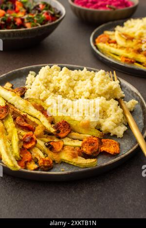 Profitez d'un copieux petit déjeuner ou déjeuner avec millet, courgettes cuites au four et carottes, accompagné d'une salade fraîche de légumes et d'herbes de saison, de petits pains aux pois chiches, Banque D'Images