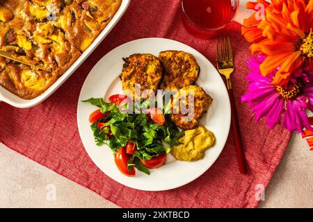 Profitez d'un délicieux petit déjeuner sain avec des crêpes de courgettes, de la laitue fraîche et des tomates complétées par une compote de cerises et une tranche de tarte aux pêches fo Banque D'Images