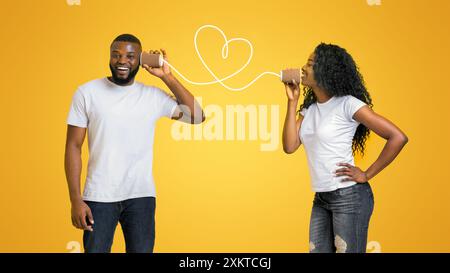 Belle black girl in aime parler par téléphone peut avec son petit ami, l'amour est dans l'air, jaune fond studio, l'espace vide Banque D'Images