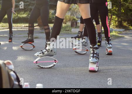 Sports activités de plein air kangu saut groupe de femmes dans la cour du parc été, les gens dans les bottes sauteurs leggings genou chaussettes. sans face, vue de dessous Banque D'Images