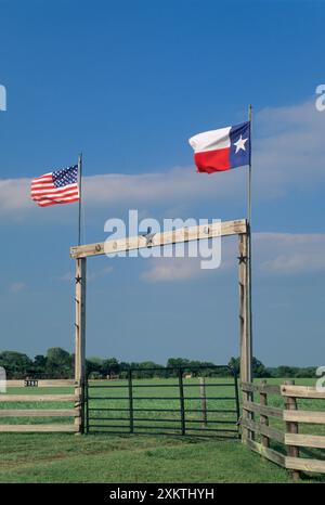 Porte de ranch en bois avec drapeaux TX et US sur l'autoroute TX 90 près d'Anderson dans le comté de Grimes, Texas, États-Unis Banque D'Images