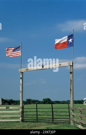 Porte de ranch en bois avec drapeaux TX et US sur l'autoroute TX 90 près d'Anderson dans le comté de Grimes, Texas, États-Unis Banque D'Images