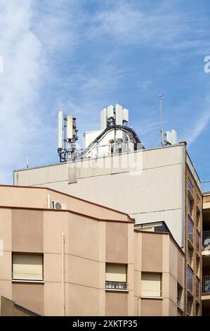 Image d'antennes de télécommunication sur le toit d'un bâtiment moderne contre un ciel bleu, mettant l'accent sur l'intégration de la technologie en milieu urbain Banque D'Images