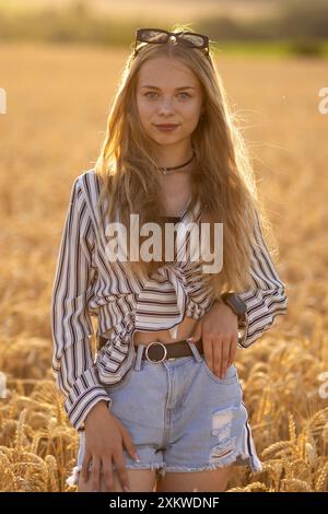 Une belle fille ukrainienne sur un champ de blé dans les rayons du soleil. Banque D'Images