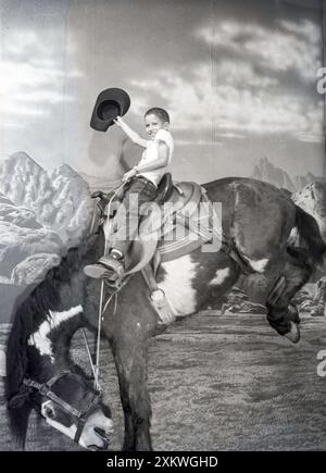 Young Boy se pose comme un bronco buster dans une opportunité de photo touristique dans le Dakota du Sud, années 1950, États-Unis Banque D'Images