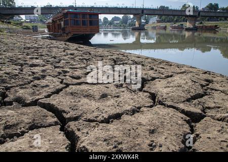 24 juillet 2024, Srinagar, Jammu-et-Cachemire, Inde : une péniche est vue près de la portion asséchée de la rivière Jhelum suite à la sécheresse continue à Srinagar, la capitale de la région himalayenne du Cachemire. Le Jammu-et-Cachemire est confronté à une hausse sans précédent des températures et des conditions météorologiques sèches. Ce changement climatique affecte non seulement l'écosystème de la région, mais aussi la vie de ses habitants. La région a connu une baisse significative des précipitations, certaines zones recevant moins de 50 % de leurs précipitations annuelles moyennes. Les experts mettent en garde contre les effets néfastes sur la masse de l'eau Banque D'Images