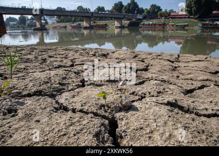 24 juillet 2024, Srinagar, Jammu-et-Cachemire, Inde : une portion asséchée de la rivière Jhelum est vue suite à la sécheresse continue à Srinagar, la capitale de la région himalayenne du Cachemire. Le Jammu-et-Cachemire est confronté à une hausse sans précédent des températures et des conditions météorologiques sèches. Ce changement climatique affecte non seulement l'écosystème de la région, mais aussi la vie de ses habitants. La région a connu une baisse significative des précipitations, certaines zones recevant moins de 50 % de leurs précipitations annuelles moyennes. Les experts mettent en garde contre les impacts négatifs sur les plans d'eau, les glaciers et k Banque D'Images