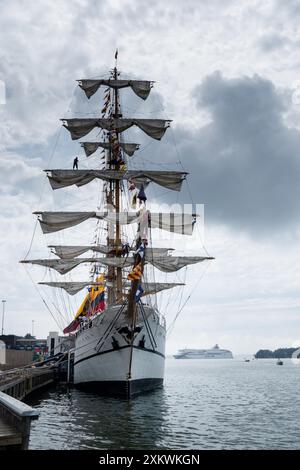 MARIEHAMN, Åland, FINLANDE - 24 JUILLET 2024 : le grand voilier Guayas de l'Équateur est assis dans le port avec un marin debout sur un mât alors que le ferry de croisière Baltic Princess tourne autour pour accoster en arrière-plan. Les marins travaillent sur les mâts. Premier jour des trois jours Åland Stage de la course de grands voiliers 2024 dans le port principal, Mariehamn, Åland, Finlande. Photo : Rob Watkins/Alamy Live News. INFO : la Tall Ships Race est un événement annuel de voile mettant en vedette des grands voiliers historiques et modernes. Il promeut l'amitié internationale et la formation des jeunes, attirant les participants et les spectateurs du monde entier pour célébrer ma Banque D'Images