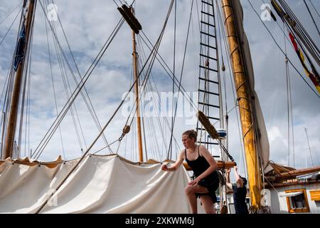 MARIEHAMN, Åland, FINLANDE - 24 JUILLET 2024 : de jeunes volontaires travaillent à bord d'un grand voilier amarré dans le port. Premier jour des trois jours Åland Stage de la course de grands voiliers 2024 dans le port principal, Mariehamn, Åland, Finlande. Photo : Rob Watkins/Alamy Live News. INFO : la Tall Ships Race est un événement annuel de voile mettant en vedette des grands voiliers historiques et modernes. Il promeut l'amitié internationale et la formation des jeunes, attirant des participants et des spectateurs du monde entier pour célébrer le patrimoine maritime et l'art de la voile traditionnelle. Banque D'Images