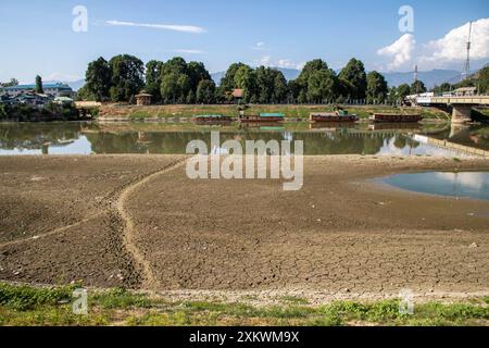 24 juillet 2024, Srinagar, Jammu-et-Cachemire, Inde : des péniches sont aperçues près de la portion asséchée de la rivière Jhelum suite à la sécheresse continue à Srinagar, la capitale de la région himalayenne du Cachemire. Le Jammu-et-Cachemire est confronté à une hausse sans précédent des températures et des conditions météorologiques sèches. Ce changement climatique affecte non seulement l'écosystème de la région, mais aussi la vie de ses habitants. La région a connu une baisse significative des précipitations, certaines zones recevant moins de 50 % de leurs précipitations annuelles moyennes. Les experts mettent en garde contre les effets néfastes sur la masse de l'eau Banque D'Images