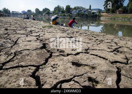 24 juillet 2024, Srinagar, Jammu-et-Cachemire, Inde : des hommes cachemiriens sont vus pêcher sur la partie sèche de la rivière Jhelum suite à la sécheresse continue à Srinagar, la capitale de la région himalayenne du Cachemire. Le Jammu-et-Cachemire est confronté à une hausse sans précédent des températures et des conditions météorologiques sèches. Ce changement climatique affecte non seulement l'écosystème de la région, mais aussi la vie de ses habitants. La région a connu une baisse significative des précipitations, certaines zones recevant moins de 50 % de leurs précipitations annuelles moyennes. Les experts mettent en garde contre les impacts négatifs sur W. Banque D'Images