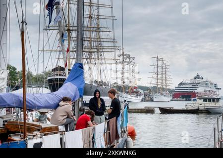 MARIEHAMN, Åland, FINLANDE - 24 JUILLET 2024 : les équipages étudiants des grands voiliers se détendent sur le pont après leur voyage de Turku dans le Finalnd continental à Mariehamn. Premier jour des trois jours Åland Stage de la course de grands voiliers 2024 dans le port principal, Mariehamn, Åland, Finlande. Photo : Rob Watkins/Alamy Live News. INFO : la Tall Ships Race est un événement annuel de voile mettant en vedette des grands voiliers historiques et modernes. Il promeut l'amitié internationale et la formation des jeunes, attirant des participants et des spectateurs du monde entier pour célébrer le patrimoine maritime et l'art de la voile traditionnelle. Banque D'Images