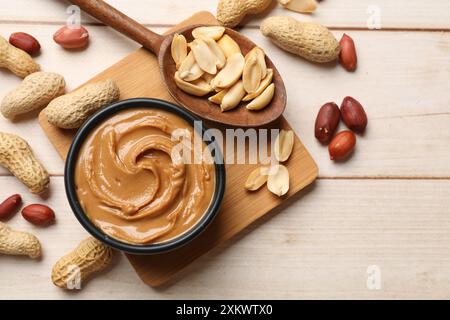 Savoureux beurre d'arachide dans un bol et des noix sur une table en bois, plat Banque D'Images