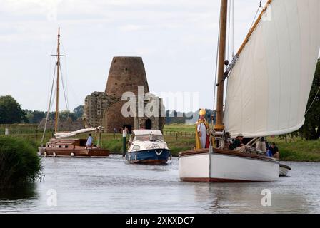 Norfolk Broads Wherry. L'évêque de Norwich le révérend Graham James arrive par Wherry, un voilier traditionnel Norfolk Broads pour prendre un service interconfessionnel sur les ruines de l'abbaye (en arrière-plan) de St Benets. Ludham Norfolk Royaume-Uni. Annuellement premier dimanche d'août. Angleterre des années 2014 2010 Royaume-Uni HOMER SYKES Banque D'Images