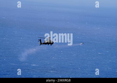 Un hélicoptère Apache AH-64 attaché au 2e bataillon, 6e escadron de cavalerie, 25e brigade d'aviation de combat, 25e division d'infanterie tire un missile AGM-114 Hellfire vers le quai de transport amphibie de classe Austin désaffecté USS Dubuque pour une longue période planifiée, exercice de naufrage de feux réels (SINKEX) au large de la côte de Kauai pendant l'exercice Rim of the Pacific (RIMPAC) 2024, 11 juillet. Chaque SINKEX est effectué en stricte conformité avec les lois, règlements et permis environnementaux américains applicables afin de minimiser les dommages environnementaux potentiels. Vingt-neuf Nations, 40 navires de surface, trois sous-marins, 1 Banque D'Images