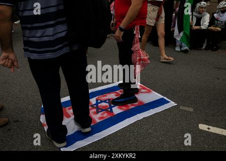 Washington DC, États-Unis, États-Unis, 24 juillet 2024. Des manifestants pro-palestiniens sont debout sur le drapeau d'Israël lors d'une manifestation autour du National Mall, Washington DC, États-Unis, le 24 juillet 2024. Des milliers de personnes sont rassemblées pour des manifestations avec une série de revendications, y compris la libération des otages, un cessez-le-feu à Gaza et l'arrestation du premier ministre israélien Benjamin Netanyahou. Le jour où Netanyahu s’est adressé au Congrès américain à Washington alors qu’il cherchait à renforcer le soutien des États-Unis à la guerre de son pays à Gaza. (Photo de Aashish Kiphayet/ Alamy Live News) Banque D'Images