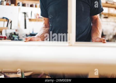 Menuisier qualifié fabriquant des meubles en bois dans un atelier confortable rempli d'outils et de sciure de bois, mettant en valeur la précision et la créativité Banque D'Images