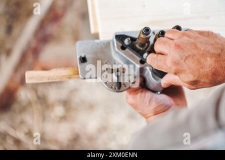 Menuisier qualifié utilisant un gabarit de cheville pour la menuiserie en bois précise dans un atelier, mettant en valeur le savoir-faire artisanal et l'expertise dans la fabrication de meubles Banque D'Images