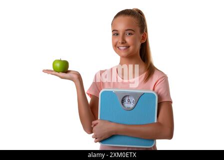 Jeune fille attrayante montrant une pomme verte sur sa paume et tenant une balance. Isolé sur fond blanc Banque D'Images