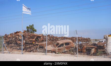 Le drapeau israélien survole une petite partie des véhicules qui ont été attaqués et incendiés le 7 octobre dans la zone frontalière de l'enveloppe de Gaza avec un ciel bleu BA Banque D'Images